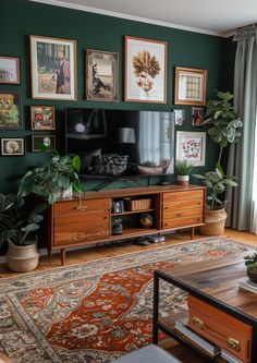 a living room with green walls and pictures on the wall, plants in vases