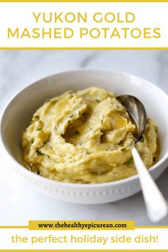 a bowl filled with mashed potatoes on top of a white table next to a spoon