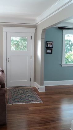 a living room with hard wood flooring and blue walls, white trim on the door