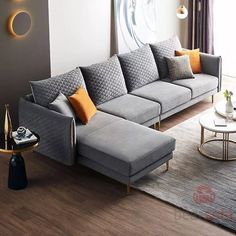 a living room with grey couches and orange pillows on the floor next to a coffee table