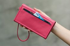 a woman's hand holding a pink purse with a credit card slot in it