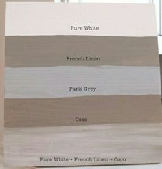 some white and brown paint samples are on a wooden block in front of a window