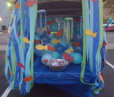 the trunk of a car decorated with blue and green balloons, streamers and decorations