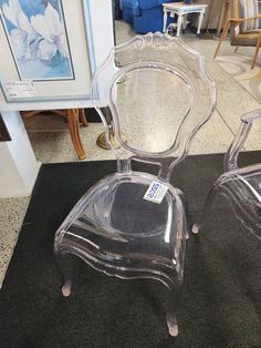 two clear chairs sitting on top of a black rug