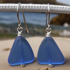 Sky Blue Recycled Glass & Sterling Silver Earrings. The glass used to create these earrings came from glass that would have been left in a landfill, but were rescued and recycled by being crushed into a sand like mixture, remelted and reformed into new glass. The beads are 15mm X 15mm.  Sterling Silver throughout.  Included are rubber stoppers for the ear wires. Not necessary, but sometimes useful. These beautiful sky blue earrings will arrive in a fabric lined gift box with a card and short sto Nickel Free Blue Recycled Glass Jewelry, Blue Sea Glass Nickel Free Earrings, Beach Earrings With Recycled Glass And Ear Wire, Blue Teardrop Sea Glass Earrings, Silver Recycled Glass Beach Earrings, Handmade Blue Sea Glass Earrings, Blue Recycled Glass Dangle Earrings, Blue Hypoallergenic Glass Earrings, Nickel-free Blue Recycled Glass Jewelry