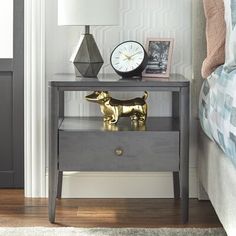 a nightstand with a golden dog figurine on it next to a clock and lamp