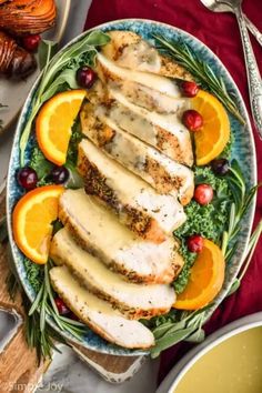 sliced chicken with oranges and cranberries on a plate next to silverware