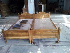 a wooden bed sitting on top of a cement floor