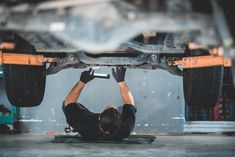 a mechanic working on the underside of a car in a garage - stock photo - images