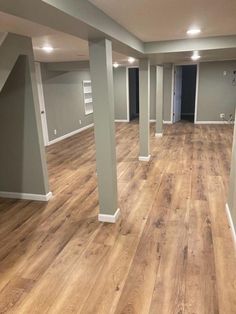 an empty room with wooden floors and white pillars in the center is painted light gray