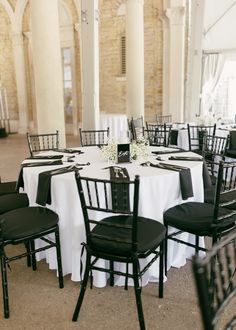 the tables are set with black chairs and white tablecloths for an elegant wedding reception