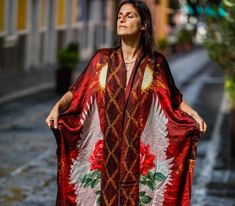 The Mystic Red Rose Silk Kimono is made out of the highest quality of satin silk. It is an extravagant expression of the Rose Priestess within each woman and brings out her radiance. The long back of the Kimono goes to the feet and has a full image of the sacred Red Rose depicted with white wings on it. The bottom of the front part of the silk Kimono is rounded up to allow more flow in the fabric. This piece is a master art piece with Digital Art designed by Phoenix Zafirah. The Red Rose represe Red Wrap Kimono For Festivals, Red Bohemian Robe With Kimono Sleeves, Elegant Red Festive Kimono, Red Bohemian Kimono For Festive Occasions, Traditional Red Kimono For Festival, Red Bohemian Kimono For Festivals, Traditional Red Kimono For Summer, Red Kimono With Kimono Sleeves For Festival, Traditional Red Summer Kimono