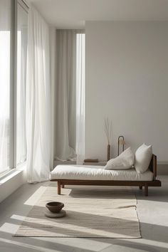 a bed sitting in the middle of a room next to a window with white curtains