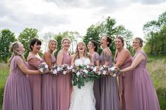 a group of women standing next to each other in front of some grass and trees