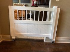 there is a white baby gate in the corner of this room that has wood flooring