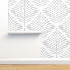 a white wall with a plant stencil on it and a wooden floor in front of it