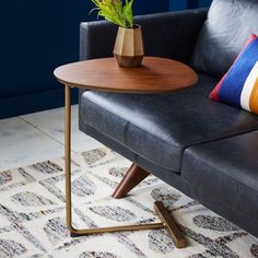 a black leather couch with a wooden table on the side and colorful pillows in front