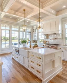 a large kitchen with white cabinets and wood flooring is pictured in this image, there are two chandeliers hanging from the ceiling