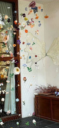 a chicken wire fence with paper flowers hanging from it's sides and on the wall