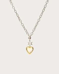 a heart shaped pendant on a chain with a small white pearl in the center and a tiny