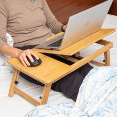 a person sitting on a bed with a laptop and mouse in front of their lap top