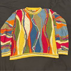 an old sweater with multicolored stripes and dots on the front, sitting on a black surface