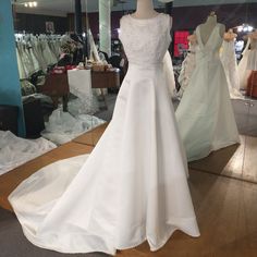 a white wedding dress is on display in a store window with mannequins behind it