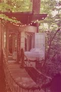 an old photo of a porch in the woods with lights strung from it's posts