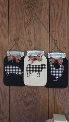 two mason jars decorated with black and white gingham plaid fabric are hanging on a wood wall