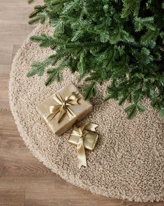 two wrapped presents sitting on top of a rug next to a tree