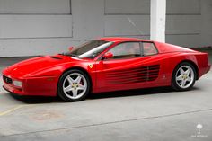 a red sports car is parked in front of a garage door with green frame around it