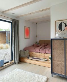 a bedroom with a bed, dresser and window in the corner that looks out onto the yard