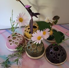 three ceramic vases with flowers in them on a table