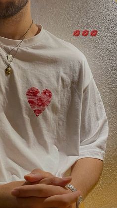 a man wearing a white t - shirt with a heart on it's chest