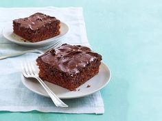 two white plates topped with brownies on top of a blue table cloth next to a fork