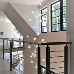 an open staircase with lights hanging from the ceiling and windows on either side of it