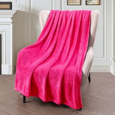 a pink blanket sitting on top of a chair in a living room next to a fireplace