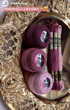 three skeins of purple yarn sitting on top of a gold plate next to each other