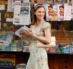 a woman standing in front of a store holding a book