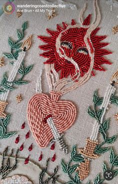 an embroidered heart and key on a white cloth with red thread, surrounded by green leaves