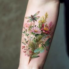 a woman's arm with flowers and dragonflies on it