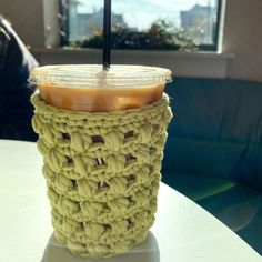 a cup with a straw in it sitting on top of a table next to a window