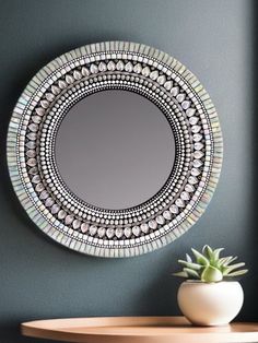 a round mirror sitting on top of a wooden table next to a potted plant