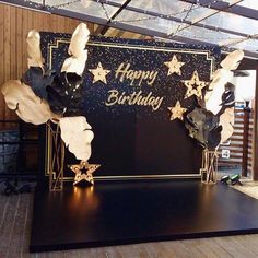 a black and gold happy birthday stage set up for a party with stars on it