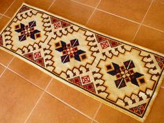 a rug is on the floor in front of a tile floor with a red and black design