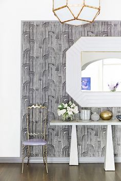 a room with a mirror, table and chair in it next to a wallpapered wall