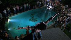 a man standing in front of a pool with his arms out to the side while people look on