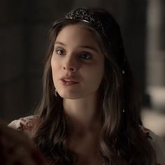 a young woman wearing a tiara looking at something in the distance with her eyes closed