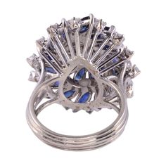 This is part of Chairish’s Fine Jewelry assortment.  Estate marquise diamond & sapphire cocktail ring, circa 1980. This cocktail ring is crafted in 18 karat white gold and features diamonds and sapphires in wire basket style setting. The center .50 carat marquise diamond has I1 clarity and F color. There are 4.25 carat total weight of sapphires and another .85 carat total weight of round diamonds. These diamonds have VS2-I1 clarity and F-H color. This diamond & sapphire cocktail ring is a size 7 Multi-stone Party Rings, Fine Jewelry Style, Fine Jewelry Multi-stone Rings For Party, Elegant Marquise Cut Multi-stone Cluster Ring, Fine Jewelry Sapphire Ring For Party, Formal Sapphire Multi-stone Ring In Cubic Zirconia, Formal Marquise Multi-stone Cluster Ring, Marquise Multi-stone Cluster Ring For Formal Occasions, Formal Multi-stone Sapphire Ring With Cubic Zirconia, Formal Marquise Cluster Ring With Multi-stone