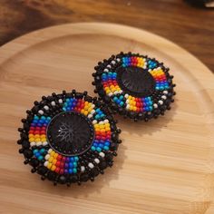 two colorful beaded earrings sitting on top of a wooden table